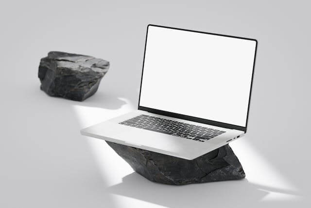 Laptop placed on a large rock symbolizing an ergonomic laptop stand in a natural outdoor setting.
