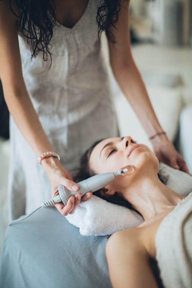 Person using a smart massage device with ambient lighting, symbolizing home relaxation and wellness technology.